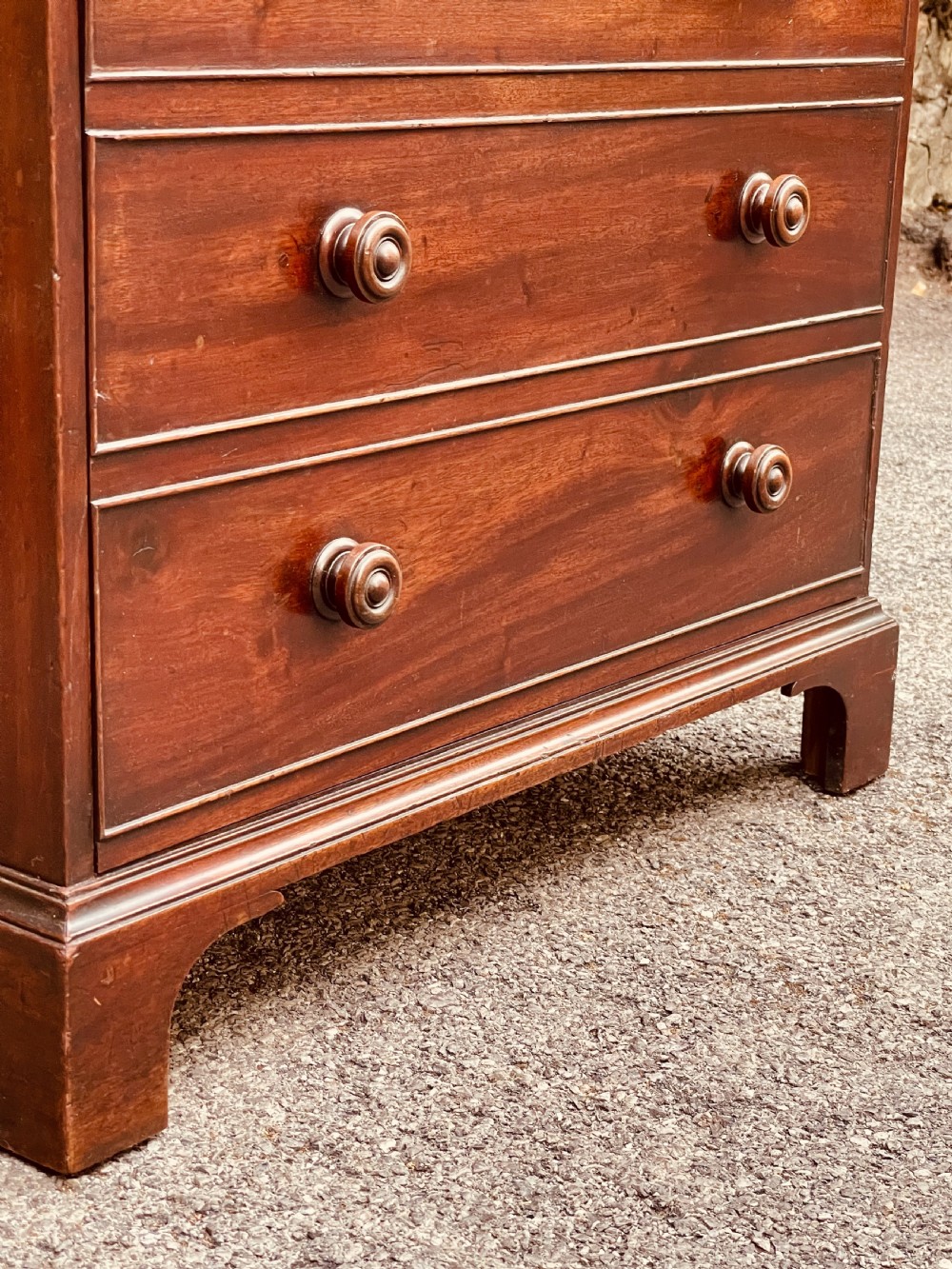 A Georgian mahogany chest featuring four drawer fronts with turned wooden handles and bracket feet. View VI