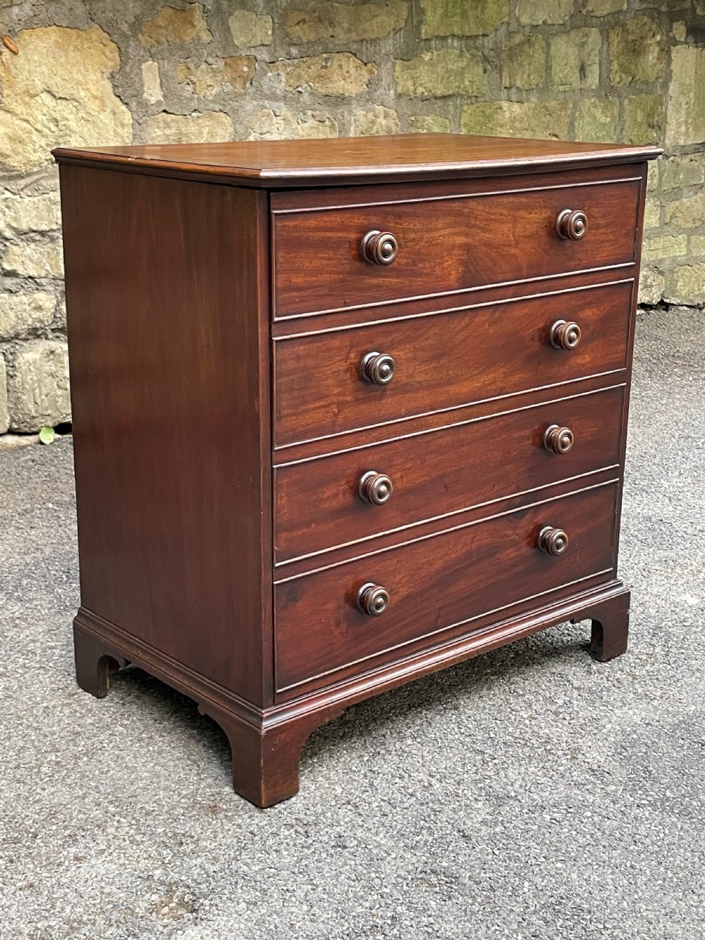 A Georgian mahogany chest featuring four drawer fronts with turned wooden handles and bracket feet. View VII
