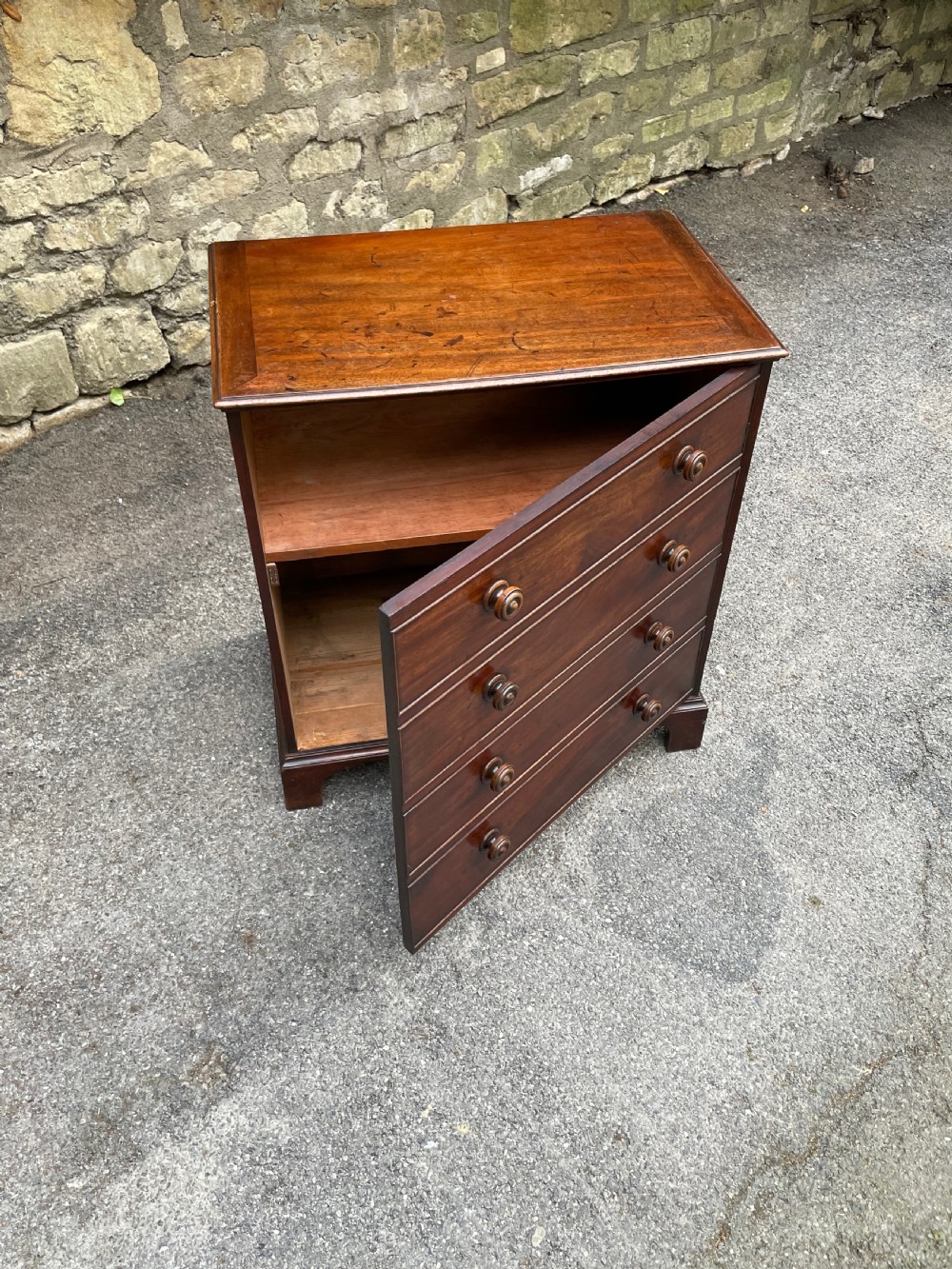 A Georgian mahogany chest featuring four drawer fronts with turned wooden handles and bracket feet. View XII