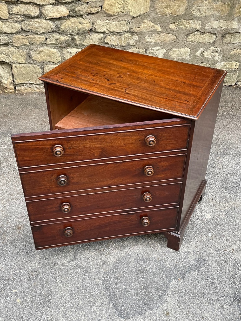 A Georgian mahogany chest featuring four drawer fronts with turned wooden handles and bracket feet. View XIV