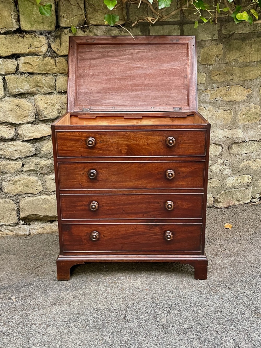 A Georgian mahogany chest featuring four drawer fronts with turned wooden handles and bracket feet. View XVI