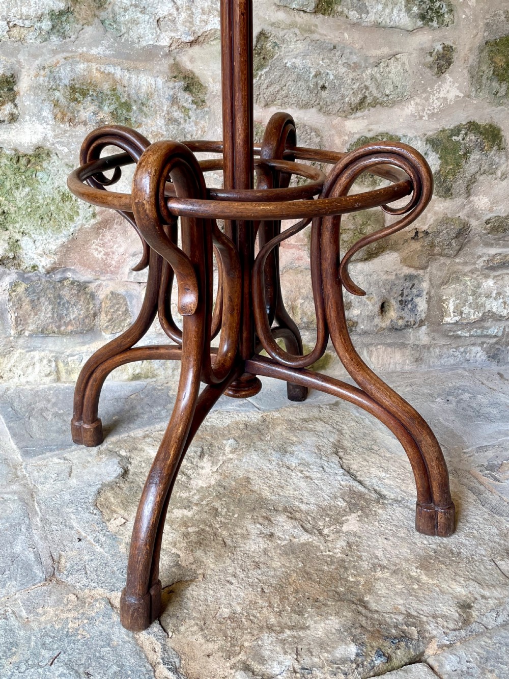 A dark brown bentwood hall stand featuring scrolled upper hooks for hats and coats, a central pole, and a curved lower frame for umbrellas. View III