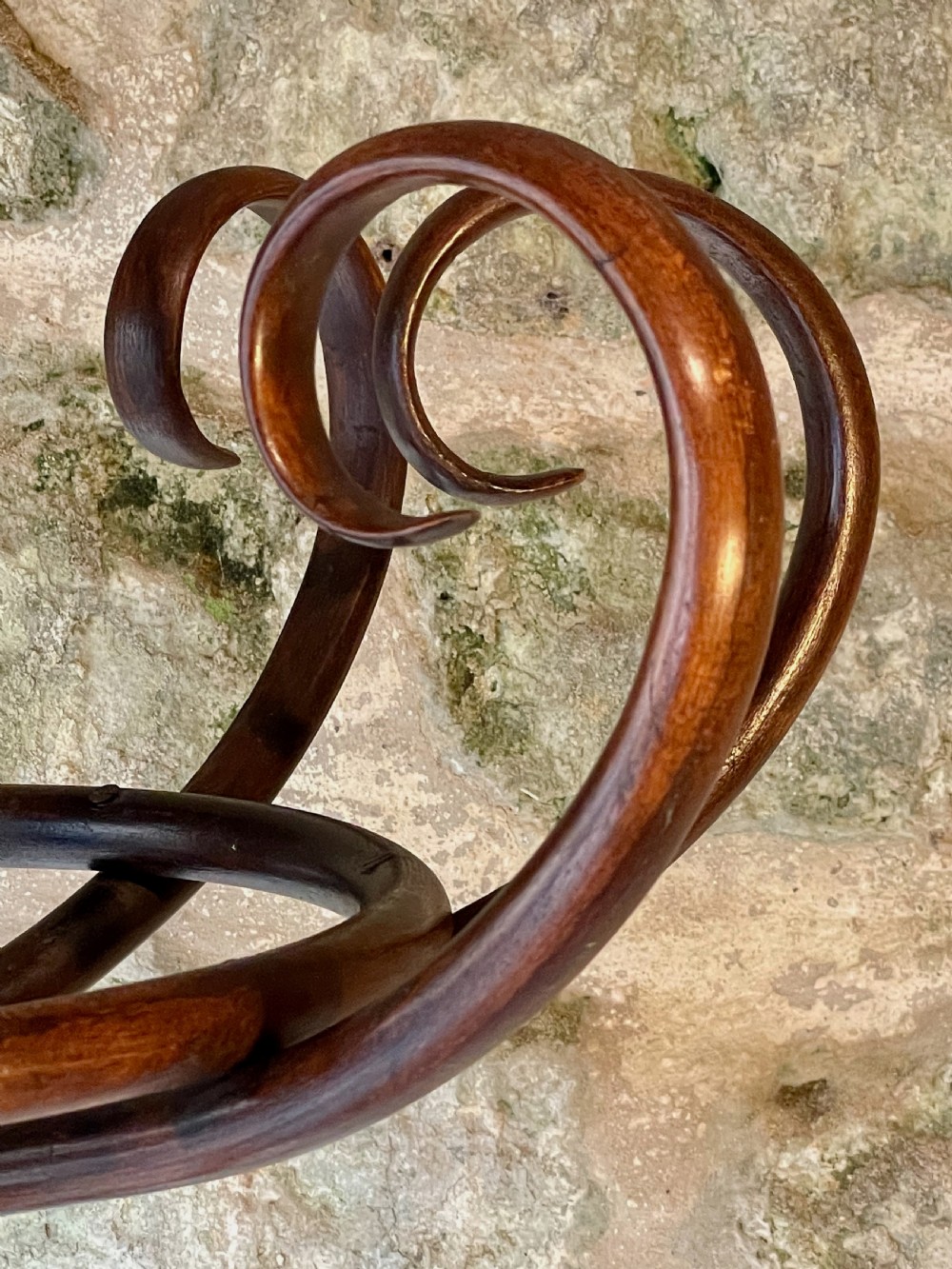 A dark brown bentwood hall stand featuring scrolled upper hooks for hats and coats, a central pole, and a curved lower frame for umbrellas. View VII