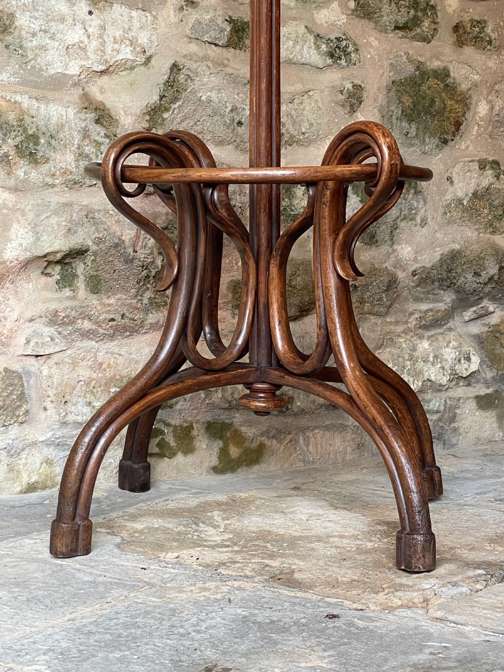 A dark brown bentwood hall stand featuring scrolled upper hooks for hats and coats, a central pole, and a curved lower frame for umbrellas. View XI