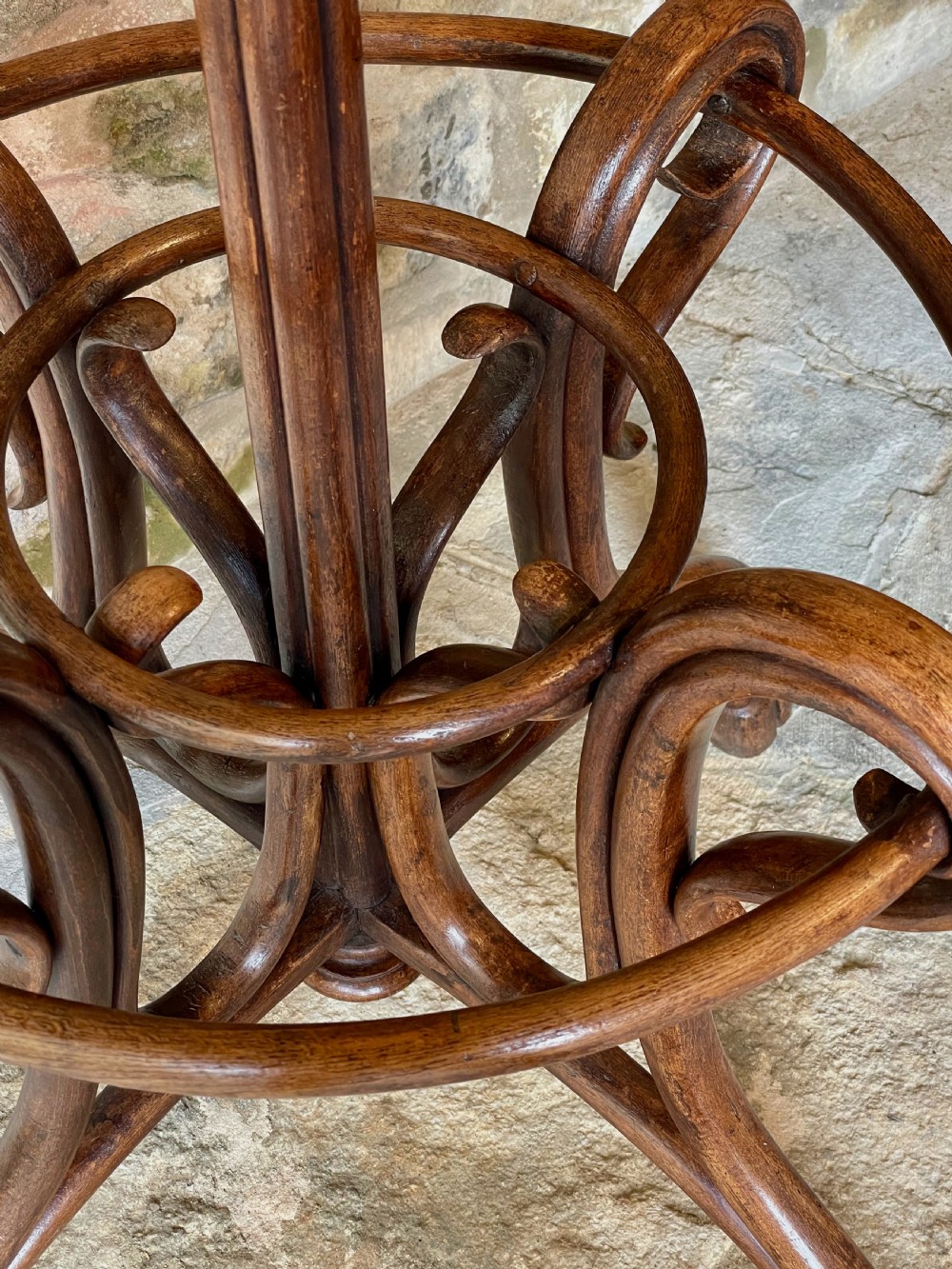 A dark brown bentwood hall stand featuring scrolled upper hooks for hats and coats, a central pole, and a curved lower frame for umbrellas. View XVIII
