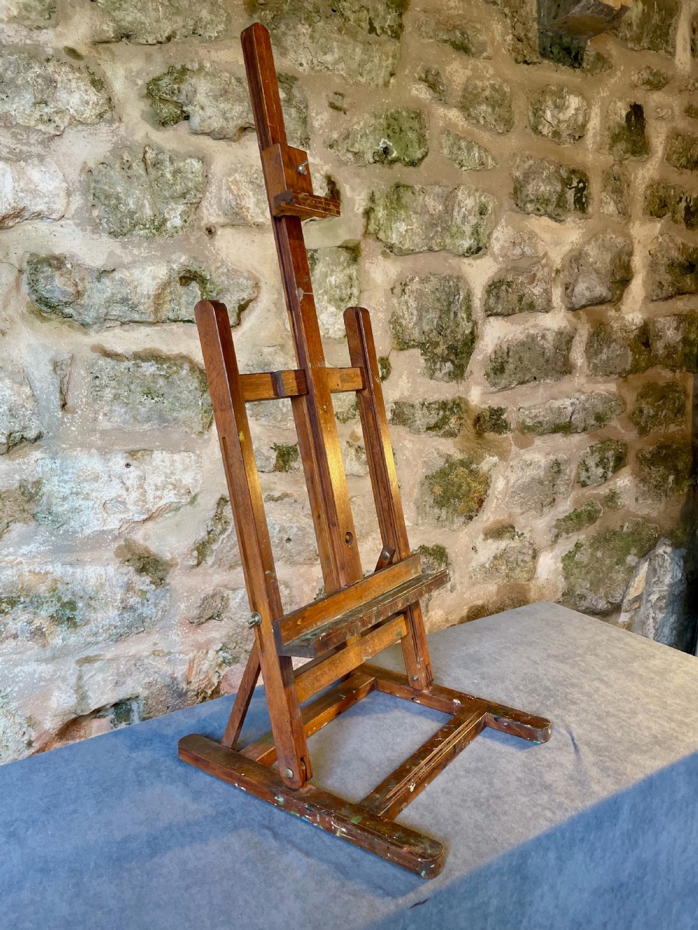 An early twentieth-century wooden tabletop artist easel with an adjustable central mast and wing nut fixings.