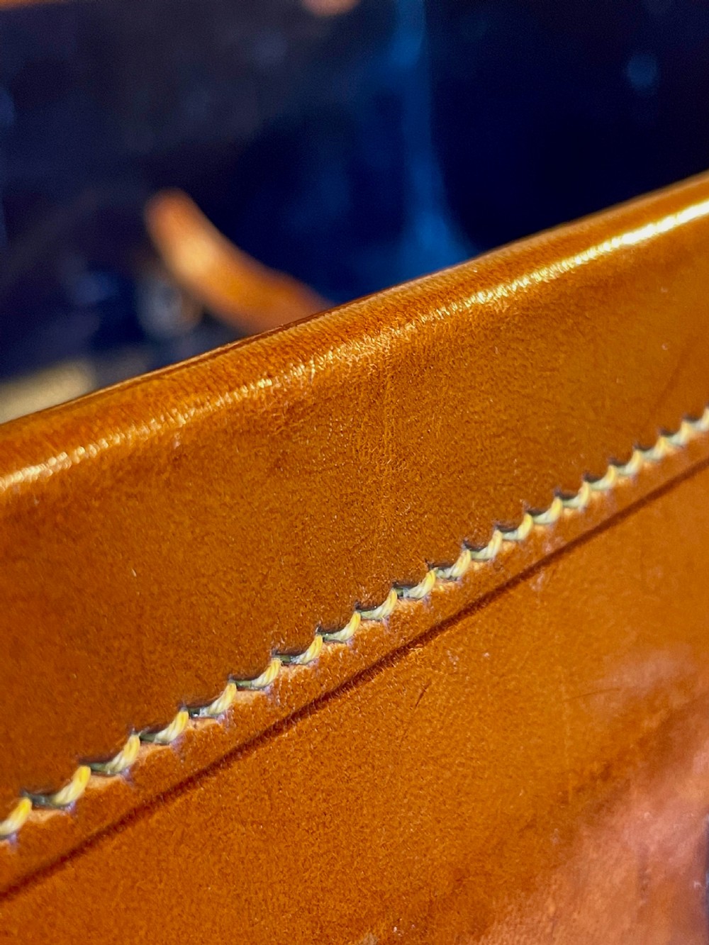 A rectangular chestnut brown leather suitcase featuring twin metal latches, hand-stitched edges, and a central leather carrying handle. View XVII