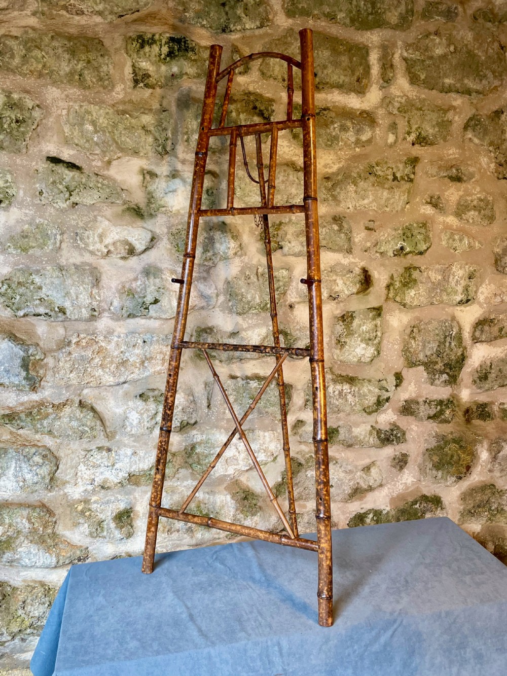 A tall Victorian freestanding easel crafted from mottled brown bamboo with cross-bracing and support pegs. View II