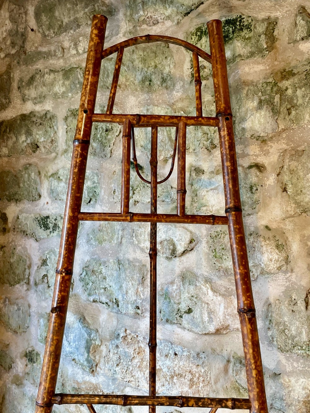 A tall Victorian freestanding easel crafted from mottled brown bamboo with cross-bracing and support pegs. View X