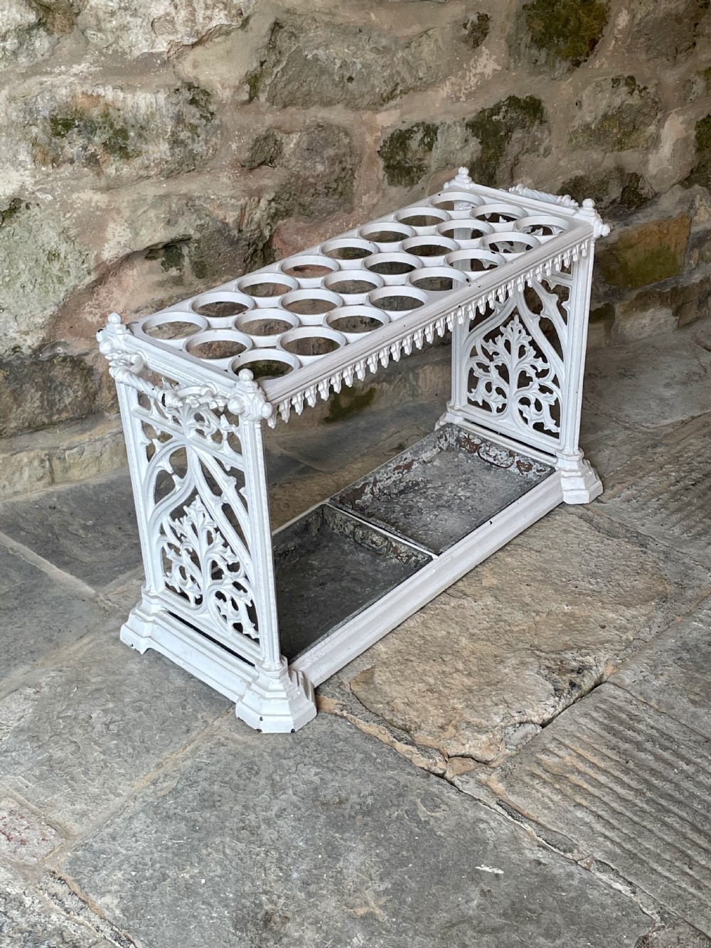 A white painted cast iron stick stand featuring openwork Gothic tracery side panels, a circular grid top section, and a removable double drip tray. View II
