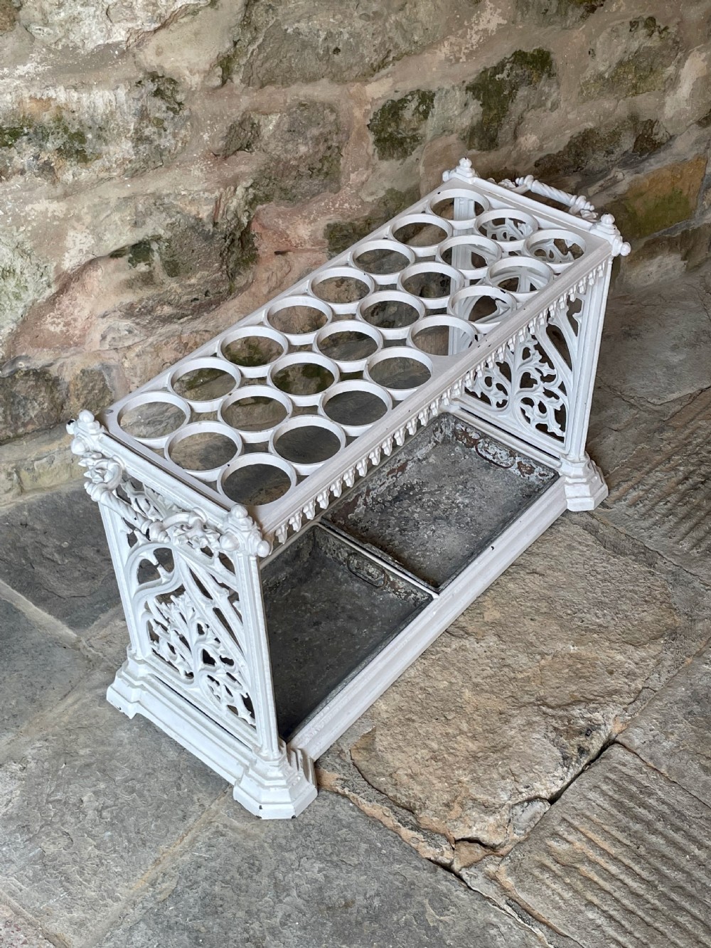 A white painted cast iron stick stand featuring openwork Gothic tracery side panels, a circular grid top section, and a removable double drip tray. View III