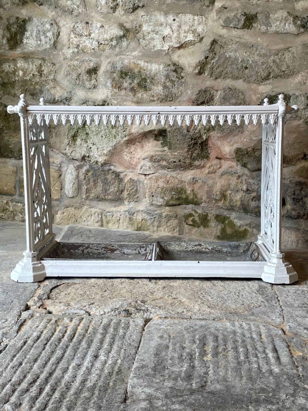 A white painted cast iron stick stand featuring openwork Gothic tracery side panels, a circular grid top section, and a removable double drip tray. View V