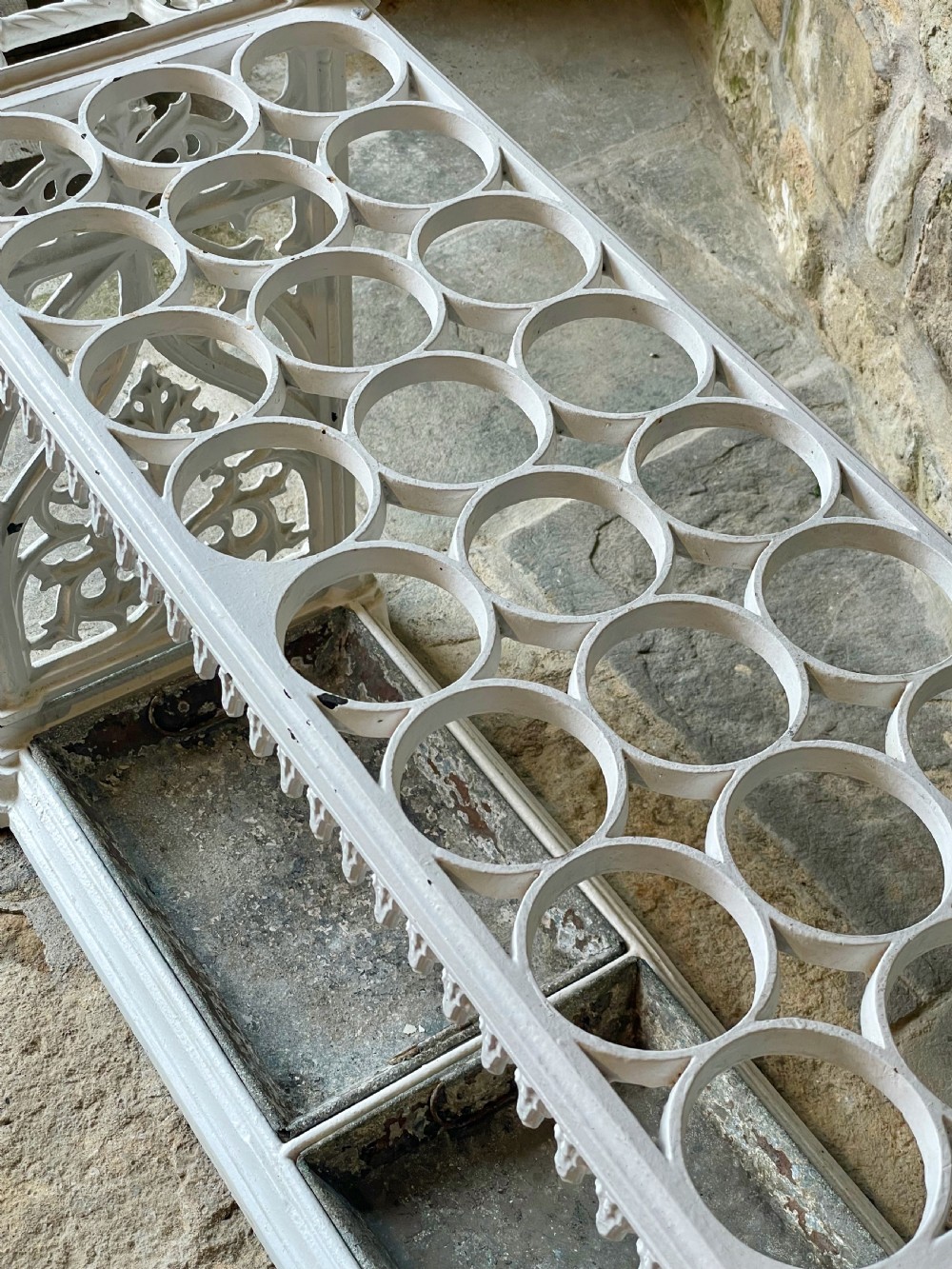 A white painted cast iron stick stand featuring openwork Gothic tracery side panels, a circular grid top section, and a removable double drip tray. View VIII