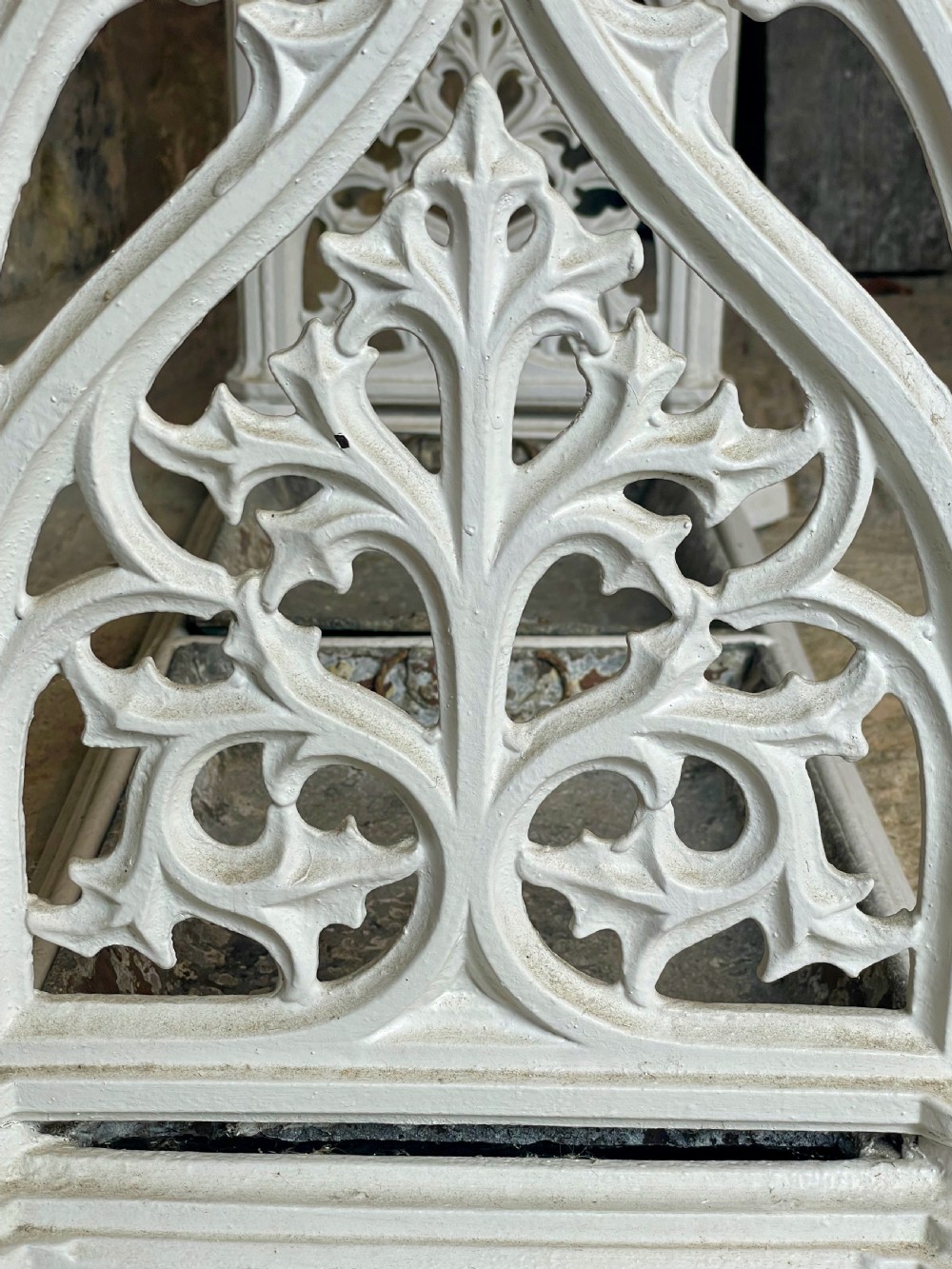A white painted cast iron stick stand featuring openwork Gothic tracery side panels, a circular grid top section, and a removable double drip tray. View X