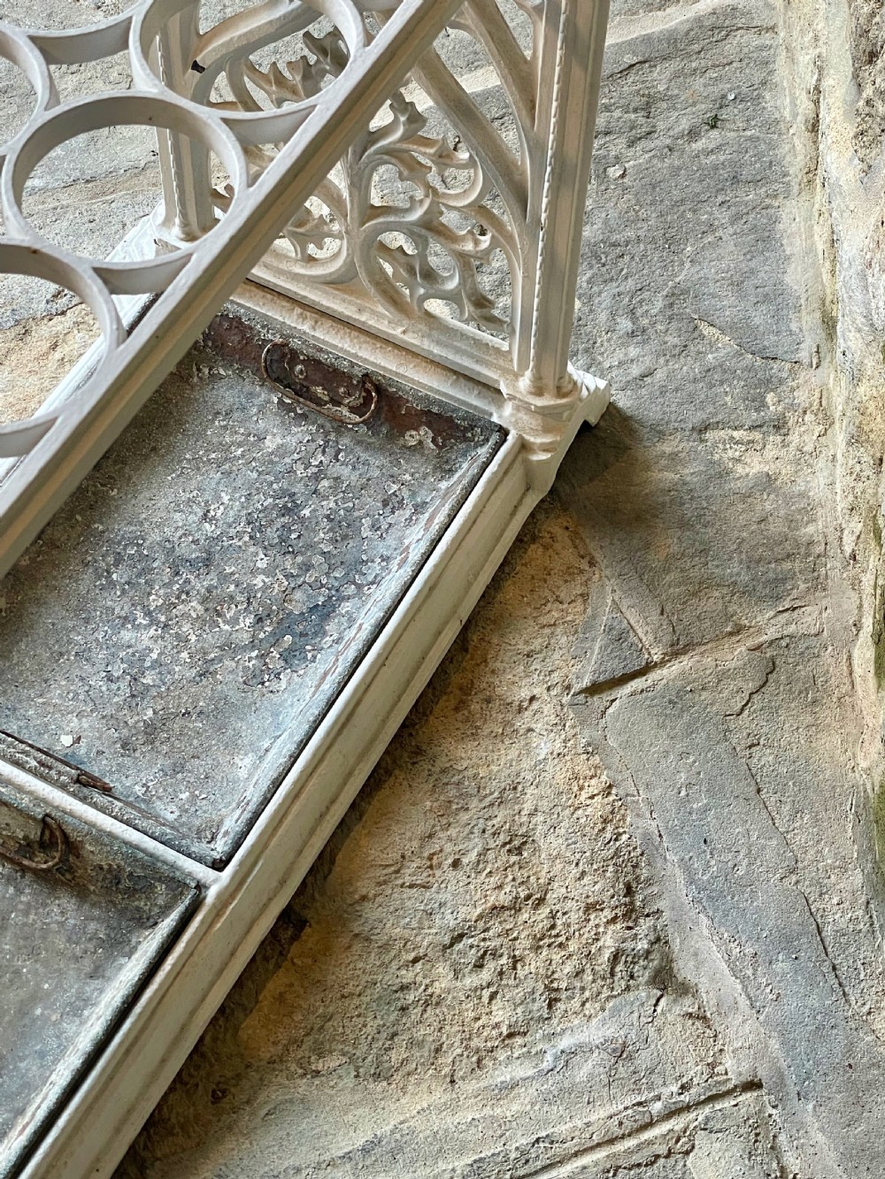 A white painted cast iron stick stand featuring openwork Gothic tracery side panels, a circular grid top section, and a removable double drip tray. View XV
