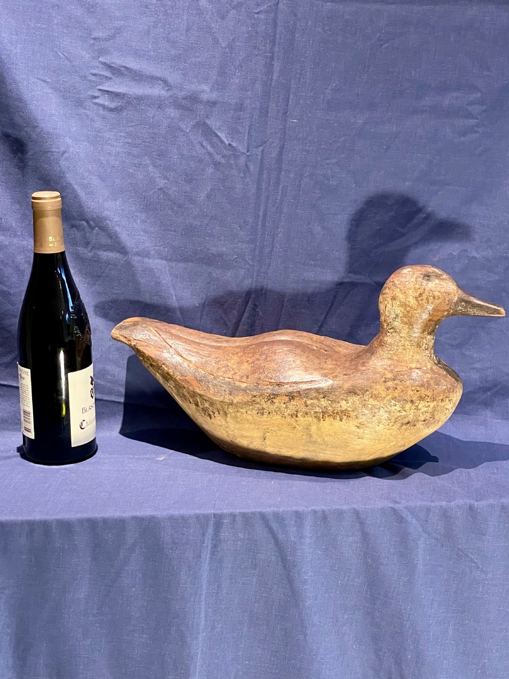 A hand-carved wooden decoy duck featuring a rounded body, defined head, and visible wood grain patination across the natural timber surface. View II