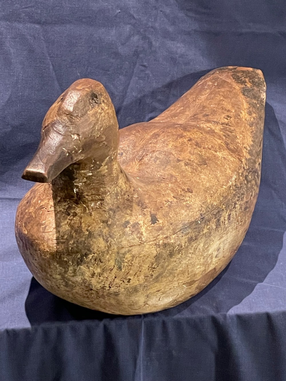 A hand-carved wooden decoy duck featuring a rounded body, defined head, and visible wood grain patination across the natural timber surface. View IV