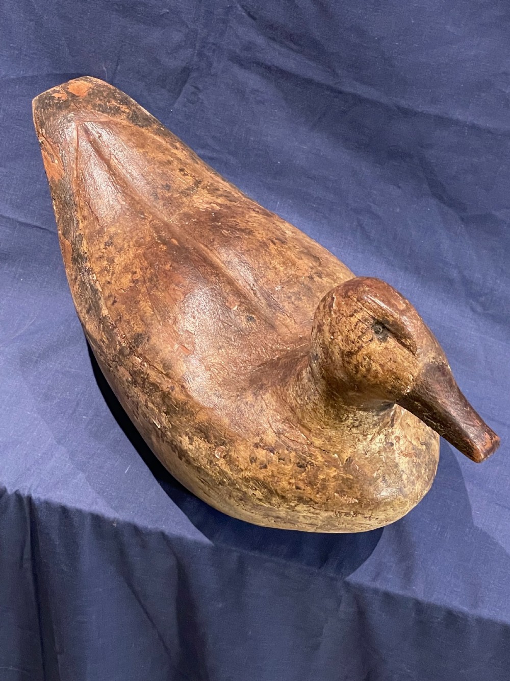 A hand-carved wooden decoy duck featuring a rounded body, defined head, and visible wood grain patination across the natural timber surface. View IX