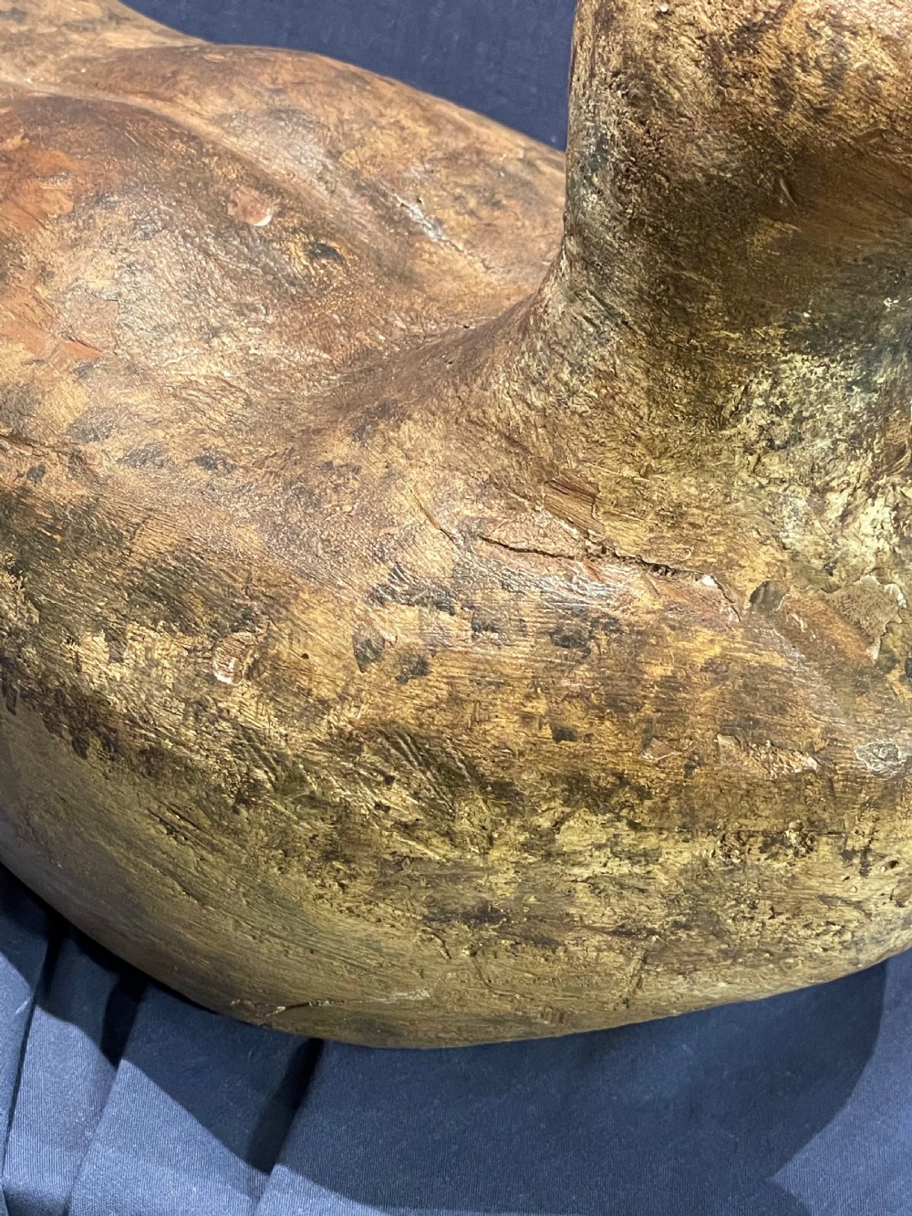 A hand-carved wooden decoy duck featuring a rounded body, defined head, and visible wood grain patination across the natural timber surface. View X