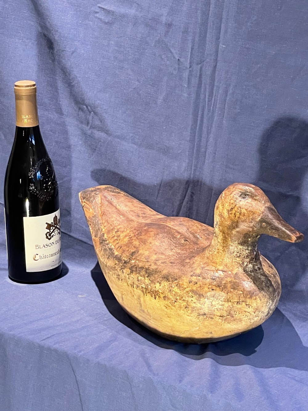A hand-carved wooden decoy duck featuring a rounded body, defined head, and visible wood grain patination across the natural timber surface. View XI