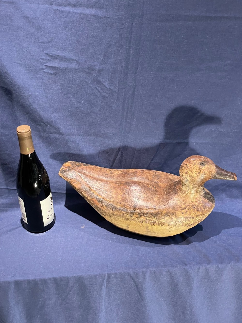 A hand-carved wooden decoy duck featuring a rounded body, defined head, and visible wood grain patination across the natural timber surface. View XII