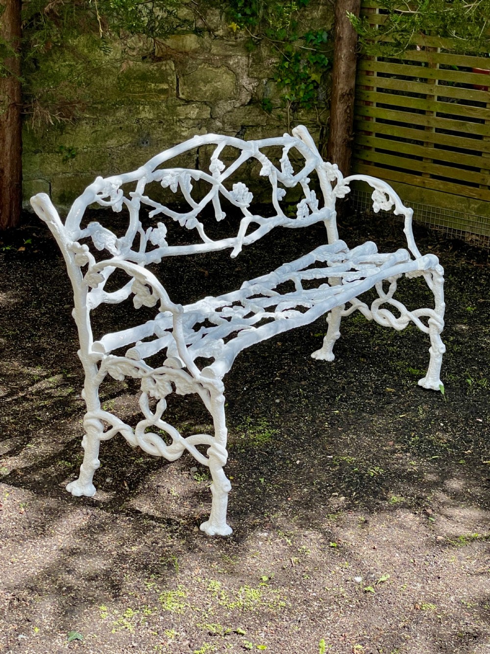 A painted white Victorian cast iron garden bench featuring an intricate intertwined branch and twig motif. View II