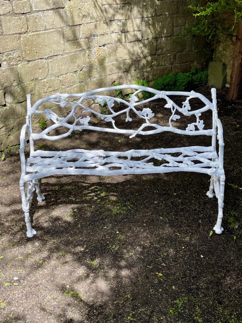 A painted white Victorian cast iron garden bench featuring an intricate intertwined branch and twig motif. View III