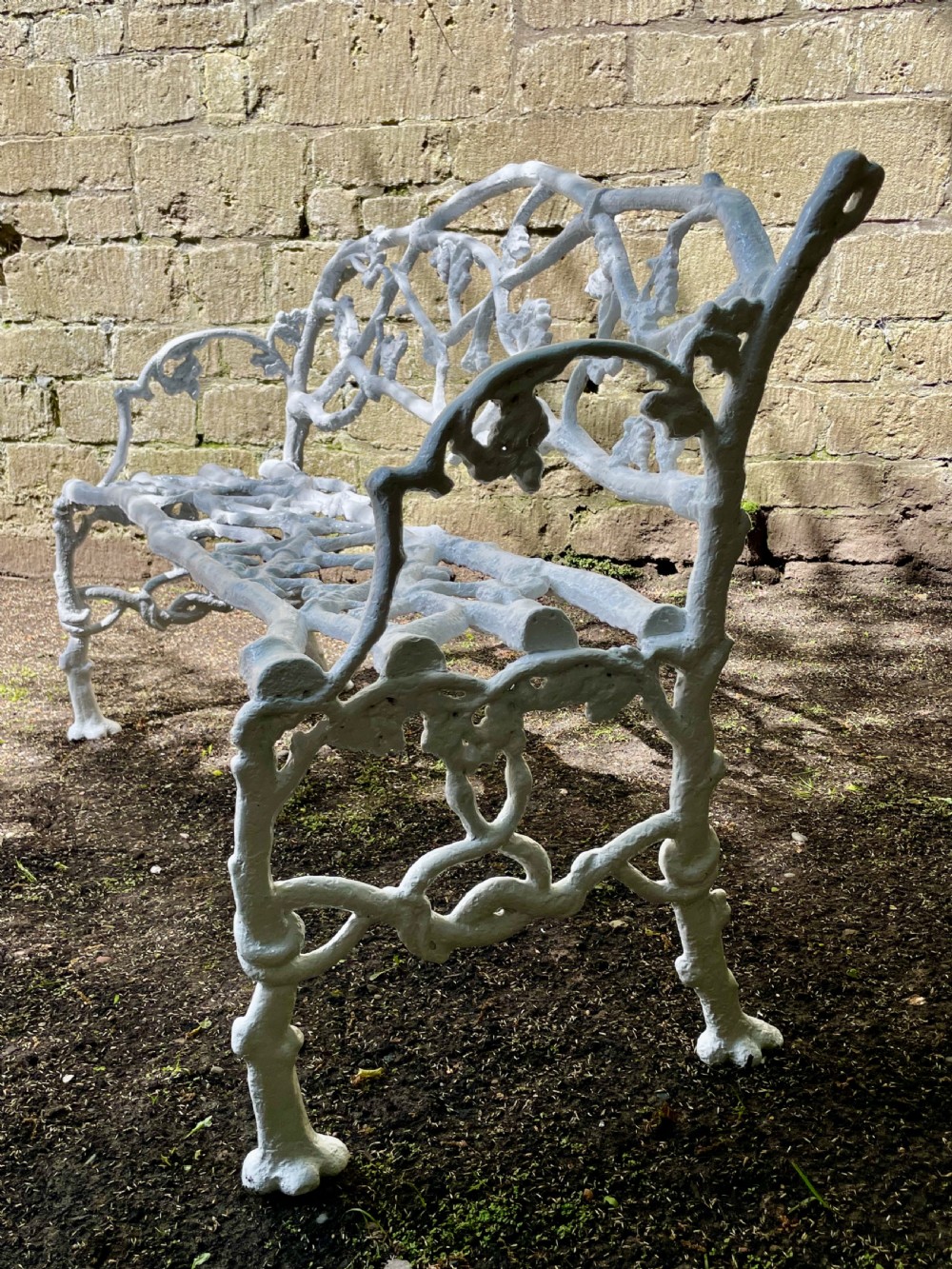 A painted white Victorian cast iron garden bench featuring an intricate intertwined branch and twig motif. View IV