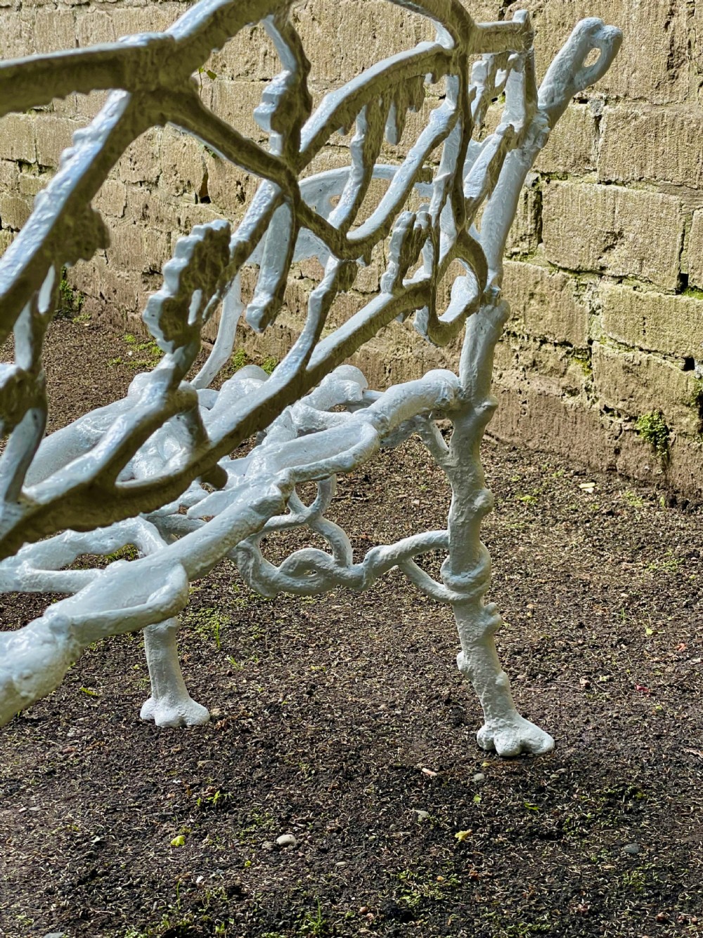 A painted white Victorian cast iron garden bench featuring an intricate intertwined branch and twig motif. View VI