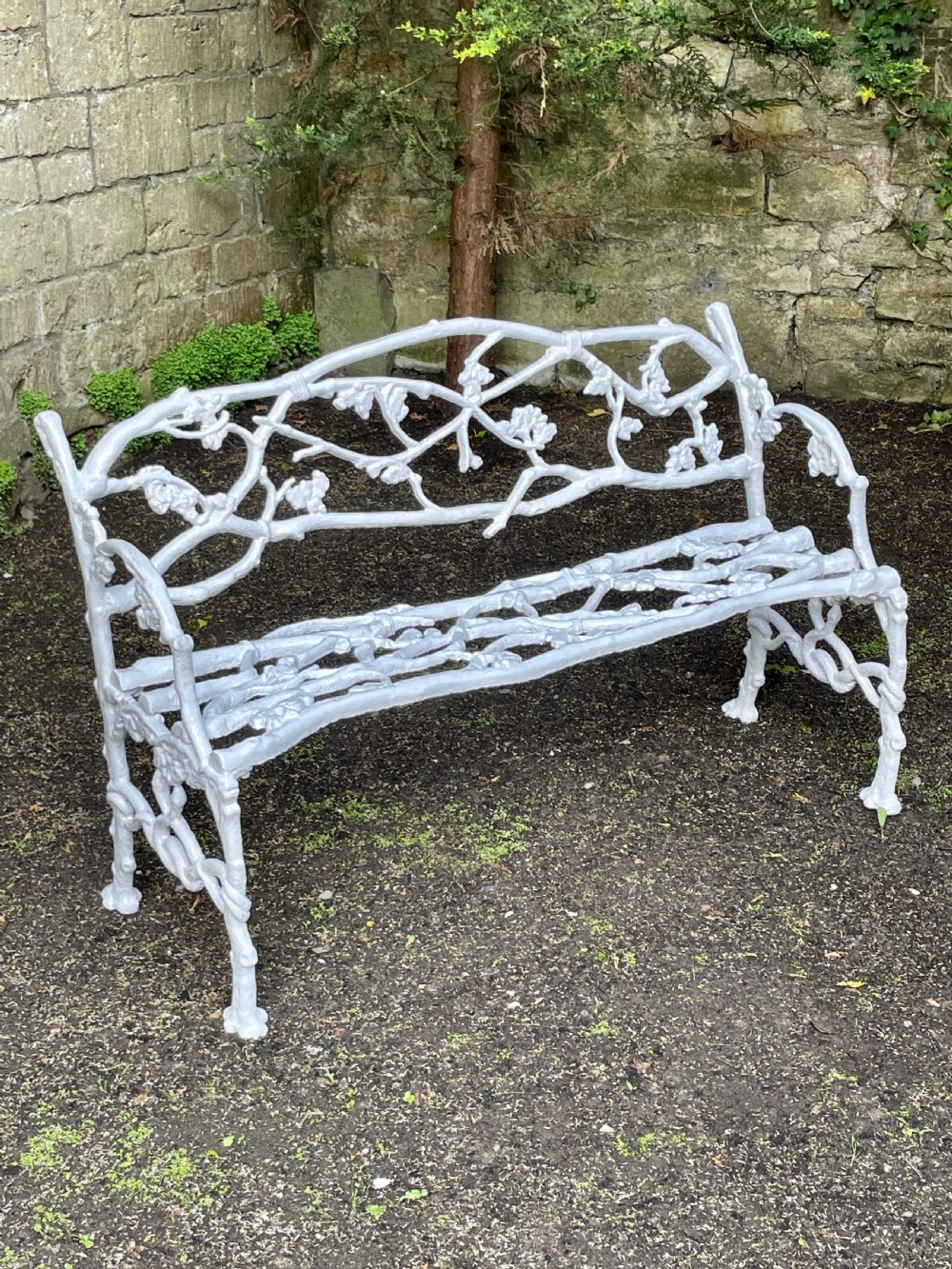 A painted white Victorian cast iron garden bench featuring an intricate intertwined branch and twig motif. View XI