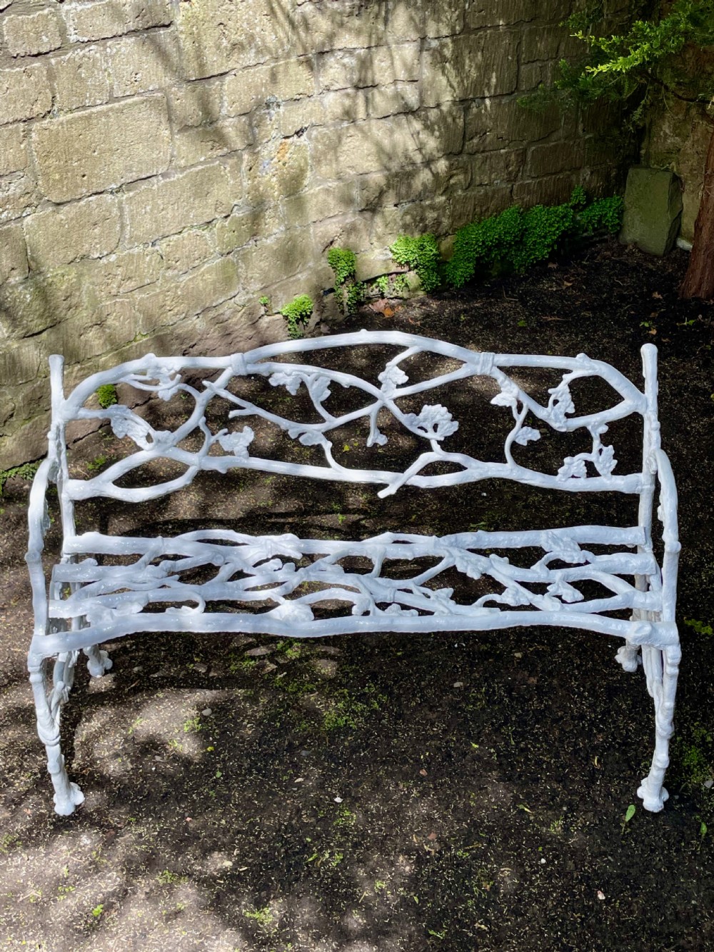 A painted white Victorian cast iron garden bench featuring an intricate intertwined branch and twig motif. View XVI
