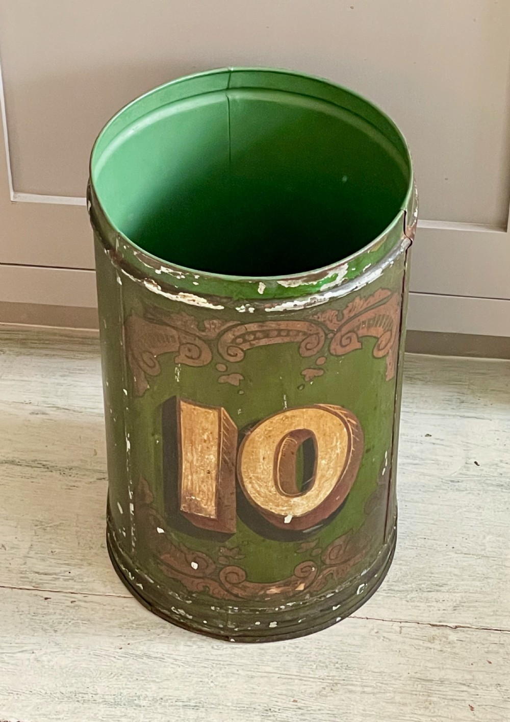 A cylindrical green painted antique metal tea canister featuring gold scrollwork and the painted number ten. View IV