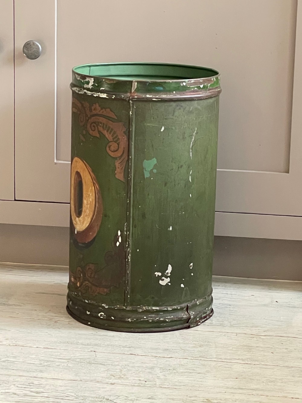 A cylindrical green painted antique metal tea canister featuring gold scrollwork and the painted number ten. View VI