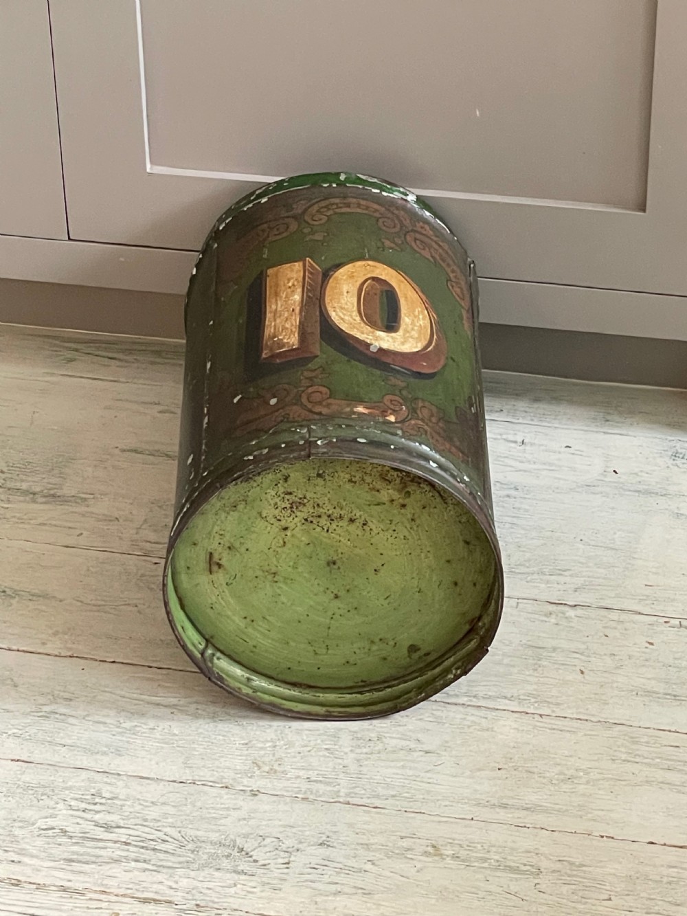 A cylindrical green painted antique metal tea canister featuring gold scrollwork and the painted number ten. View IX