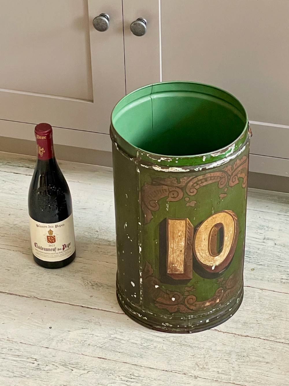 A cylindrical green painted antique metal tea canister featuring gold scrollwork and the painted number ten. View XII