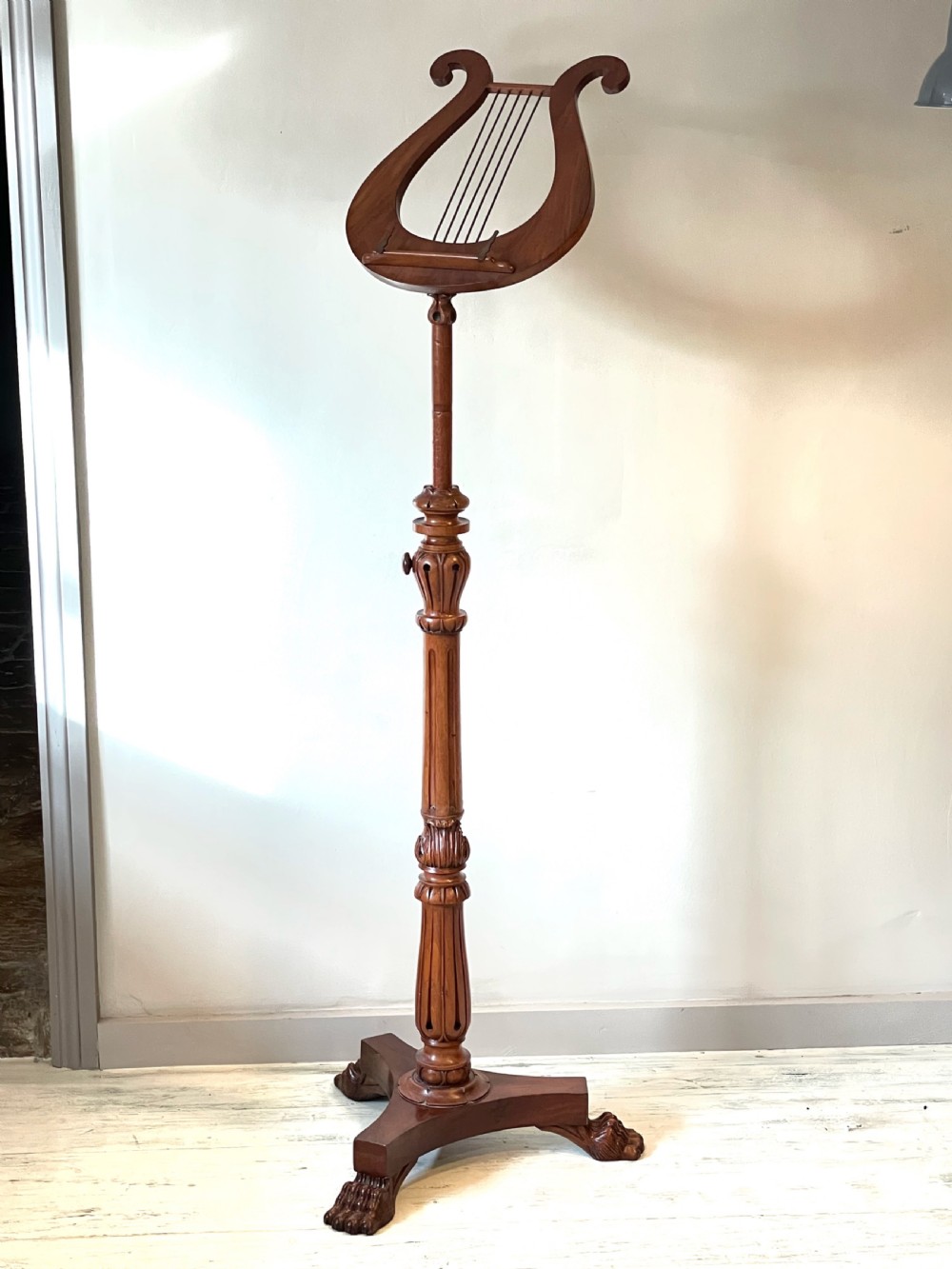 A nineteenth-century mahogany music stand featuring a lyre-shaped rest, a carved turned stem, and a triform base terminating in paw feet. View II