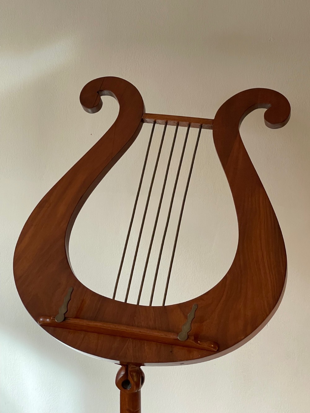 A nineteenth-century mahogany music stand featuring a lyre-shaped rest, a carved turned stem, and a triform base terminating in paw feet. View VI