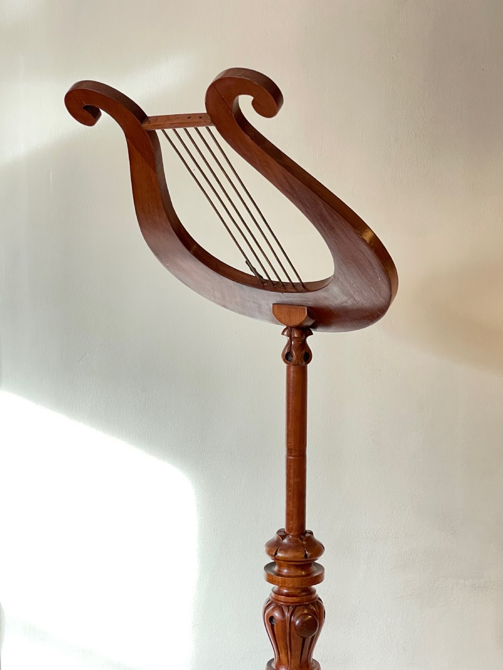 A nineteenth-century mahogany music stand featuring a lyre-shaped rest, a carved turned stem, and a triform base terminating in paw feet. View VIII