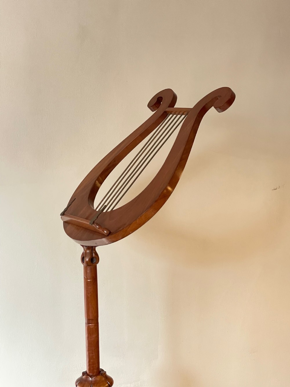 A nineteenth-century mahogany music stand featuring a lyre-shaped rest, a carved turned stem, and a triform base terminating in paw feet. View X