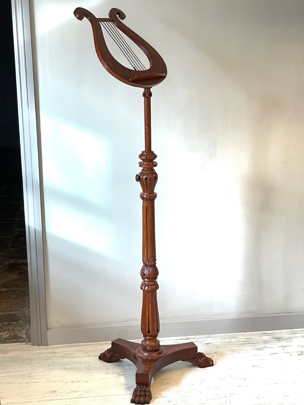 A nineteenth-century mahogany music stand featuring a lyre-shaped rest, a carved turned stem, and a triform base terminating in paw feet. View XII