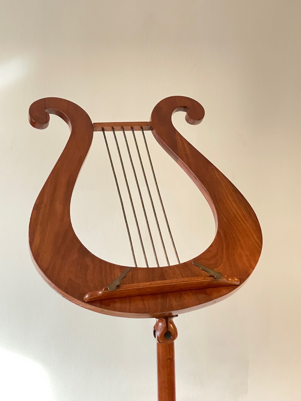 A nineteenth-century mahogany music stand featuring a lyre-shaped rest, a carved turned stem, and a triform base terminating in paw feet. View XVII