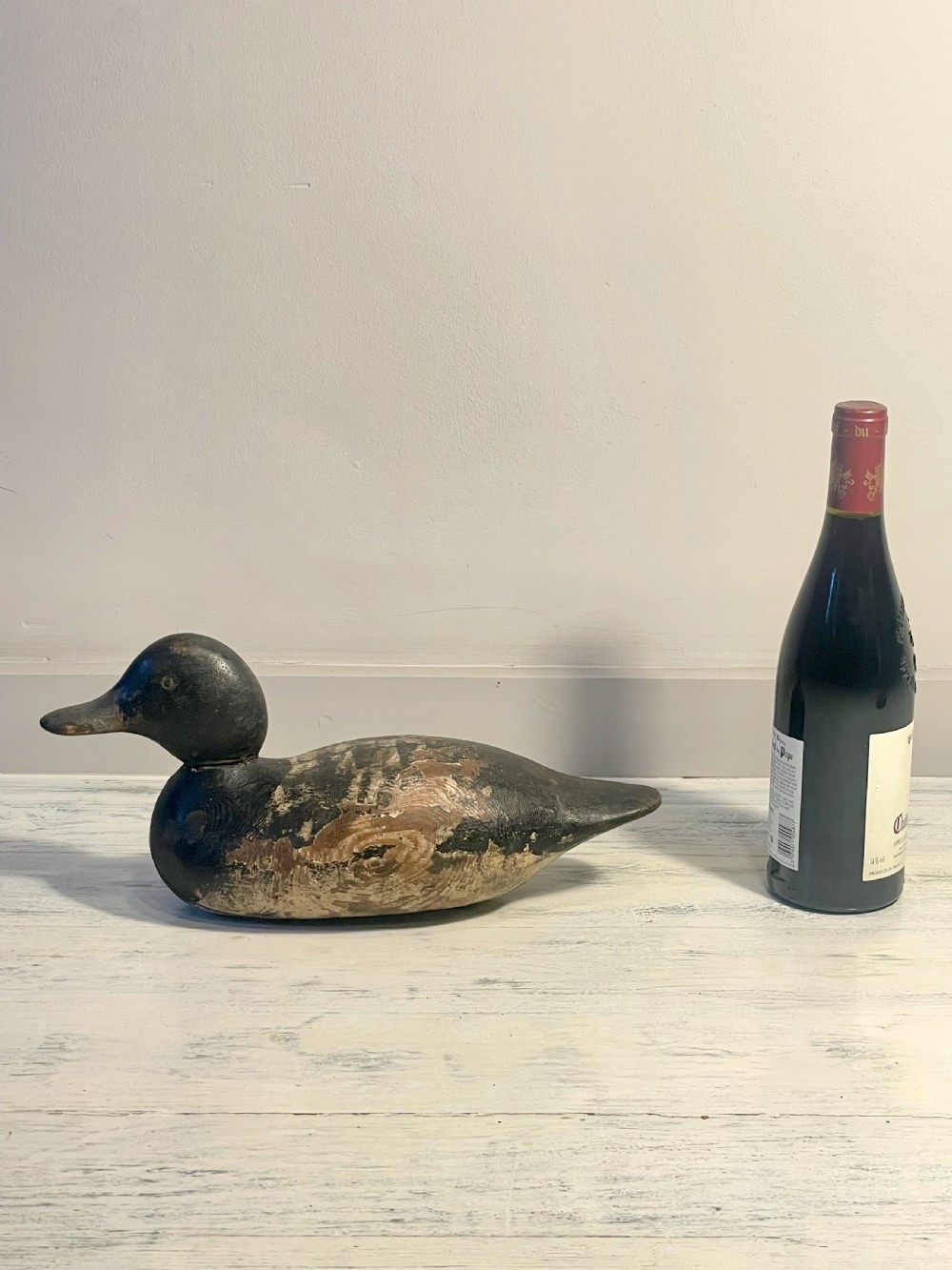 A hand-carved wooden duck decoy featuring weathered black and brown paint with exposed natural timber grain and a contoured head. View VIII