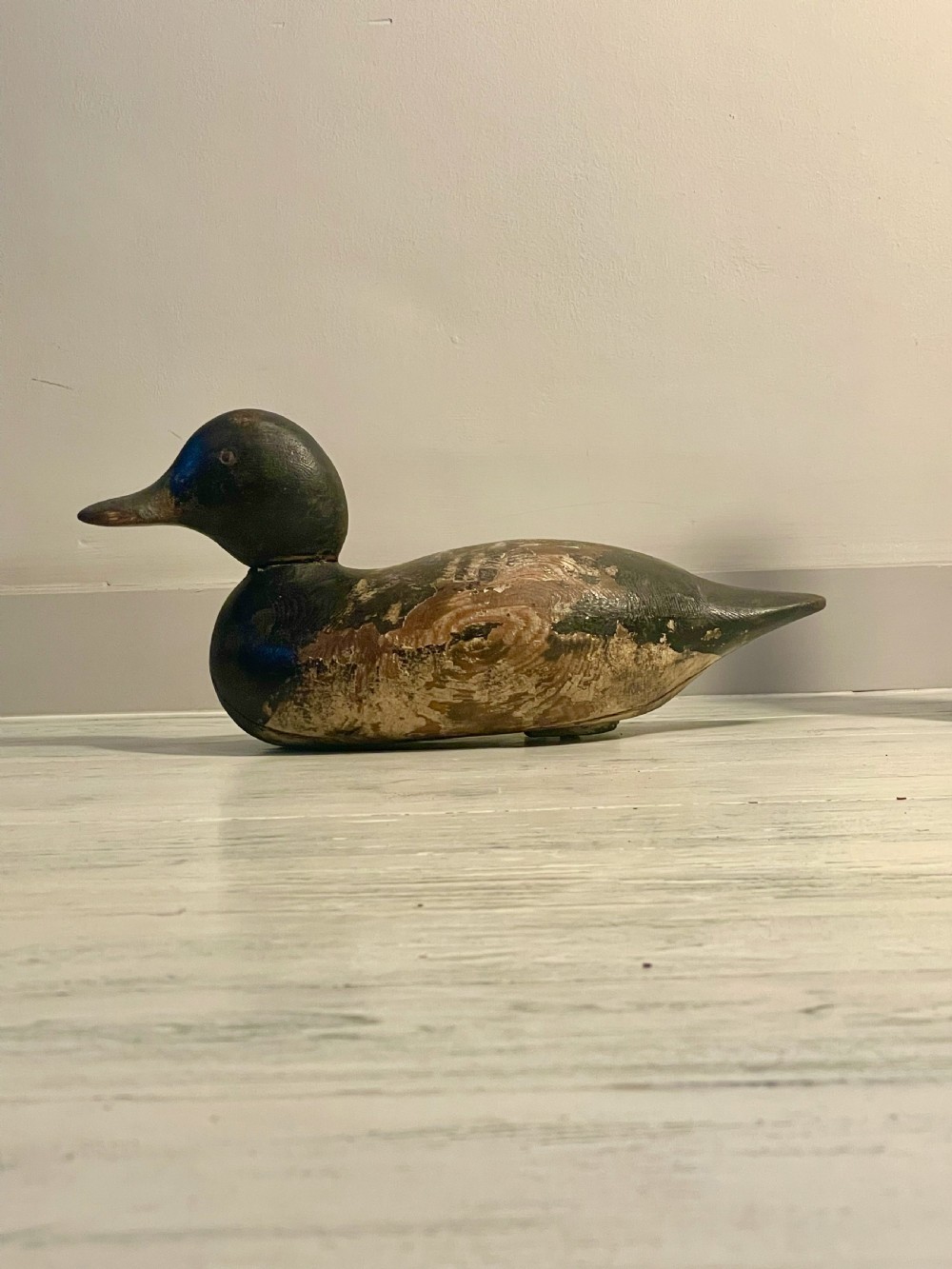 A hand-carved wooden duck decoy featuring weathered black and brown paint with exposed natural timber grain and a contoured head. View IX
