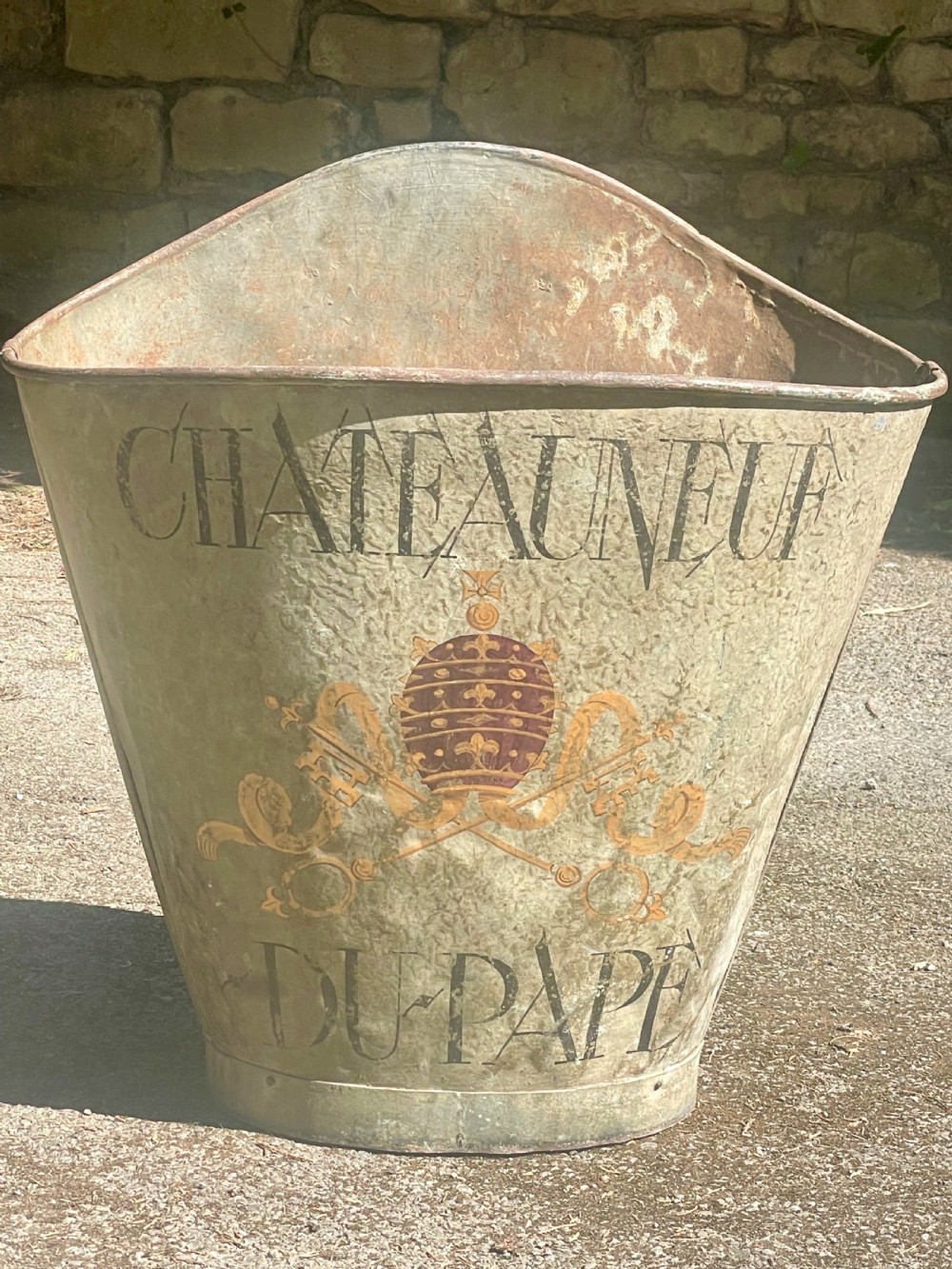 A tapered 19th-century metal grape hod featuring a distressed beige finish with hand-painted Chateauneuf-du-Pape lettering and a papal crest. View VI