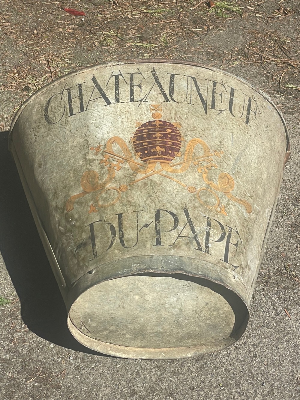 A tapered 19th-century metal grape hod featuring a distressed beige finish with hand-painted Chateauneuf-du-Pape lettering and a papal crest. View VIII