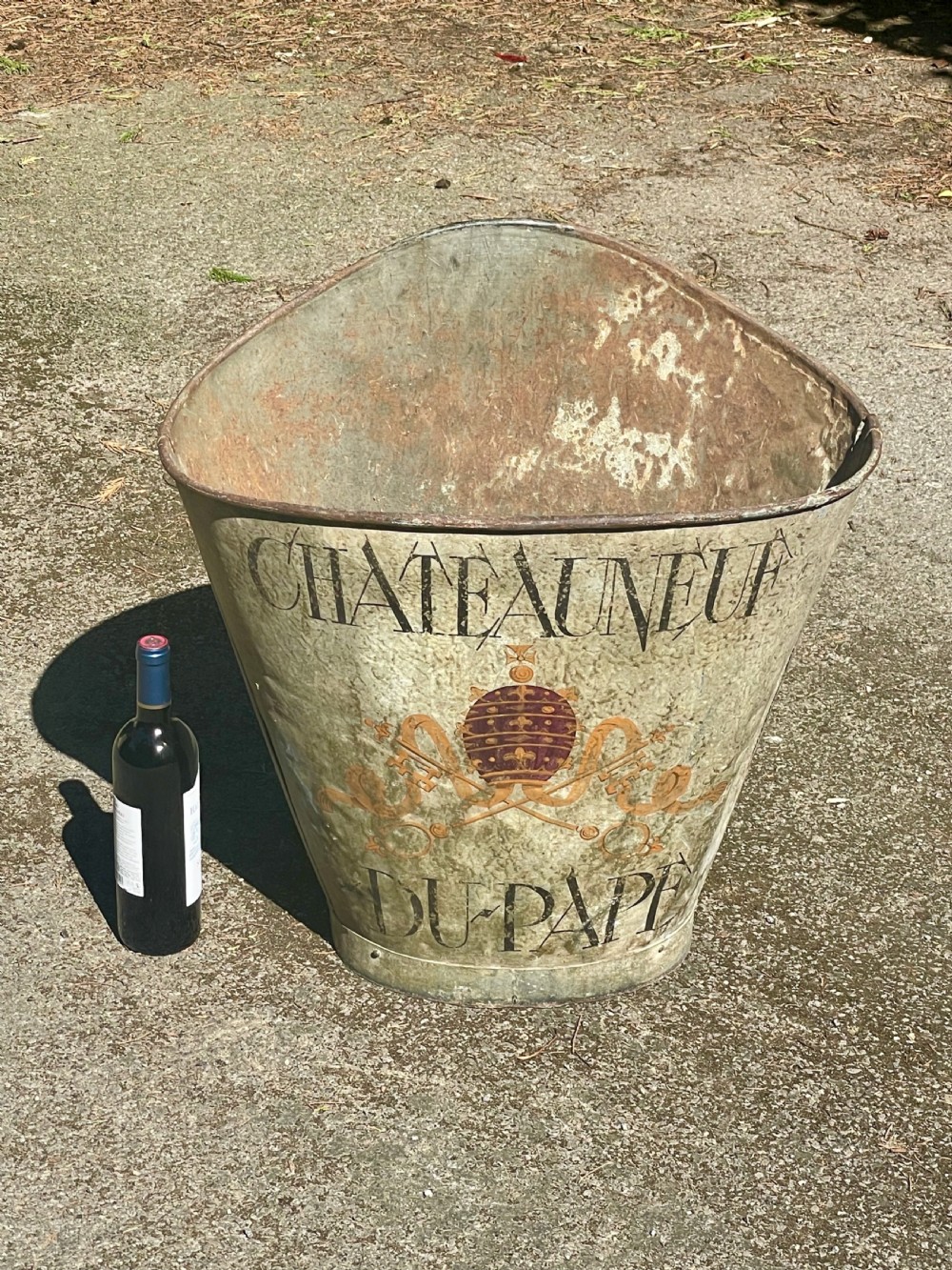 A tapered 19th-century metal grape hod featuring a distressed beige finish with hand-painted Chateauneuf-du-Pape lettering and a papal crest. View IX