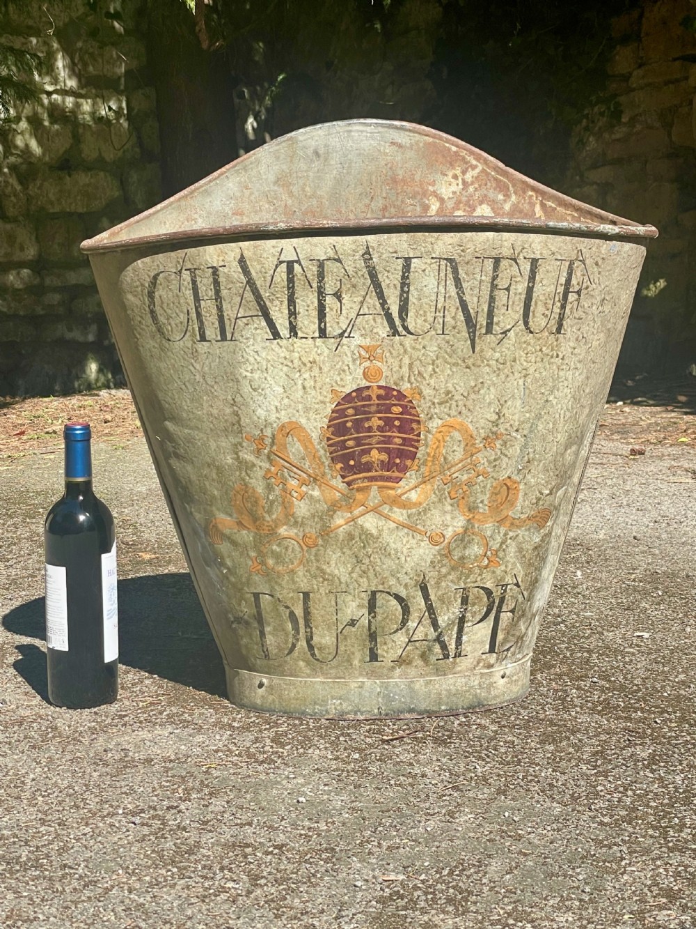 A tapered 19th-century metal grape hod featuring a distressed beige finish with hand-painted Chateauneuf-du-Pape lettering and a papal crest. View X