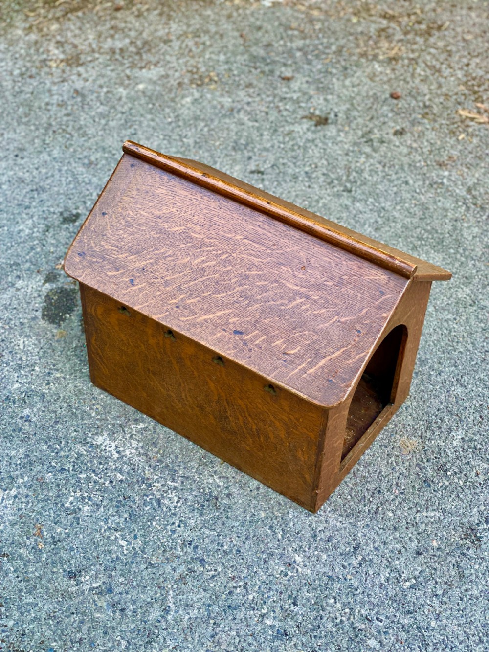 An antique Victorian warm brown oak dog kennel featuring a pitched roof, arched entrance aperture, and trefoil ventilation cutouts along the side. View IV