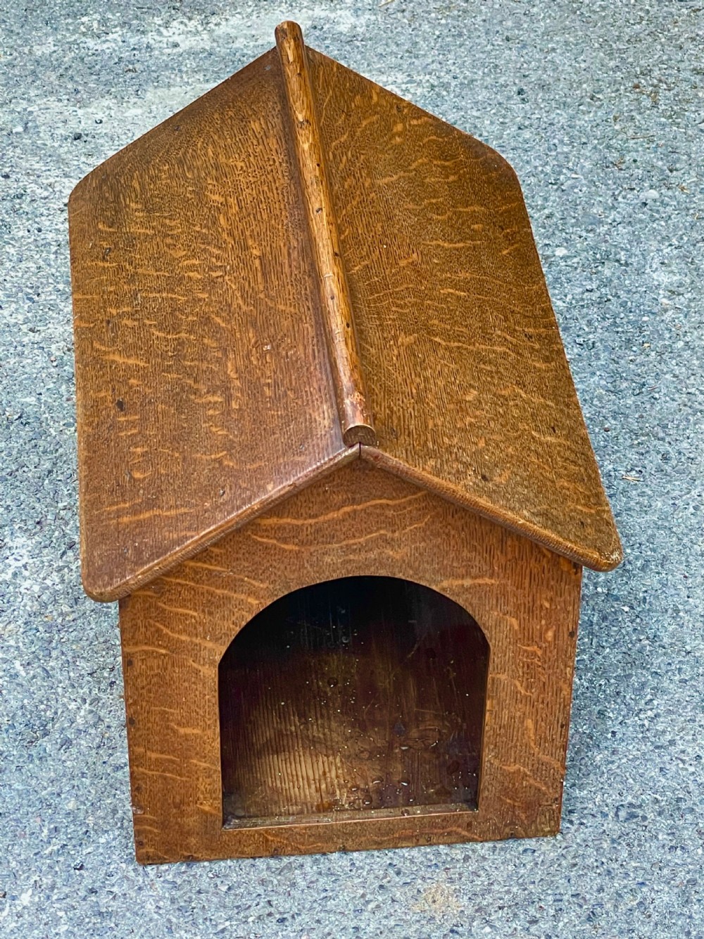 An antique Victorian warm brown oak dog kennel featuring a pitched roof, arched entrance aperture, and trefoil ventilation cutouts along the side. View VII