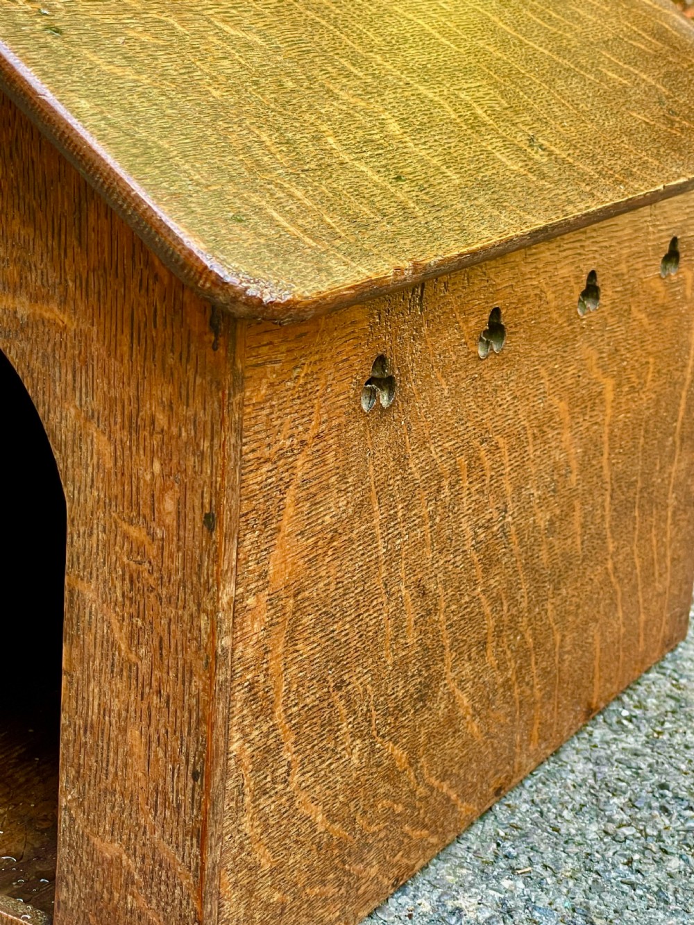 An antique Victorian warm brown oak dog kennel featuring a pitched roof, arched entrance aperture, and trefoil ventilation cutouts along the side. View VIII